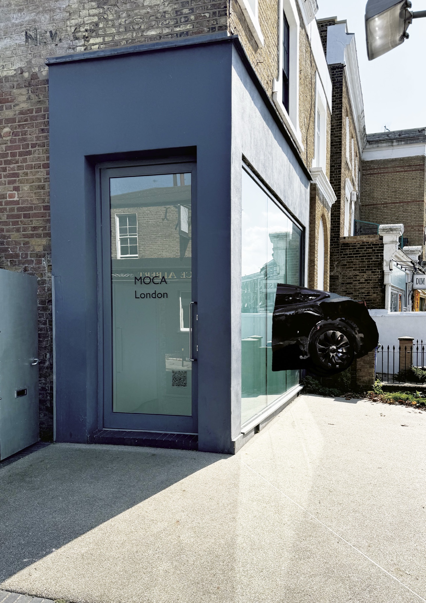 The MOCA London Project Space from the street, the rear of a black car protruding through the glass front window onto the pavement.