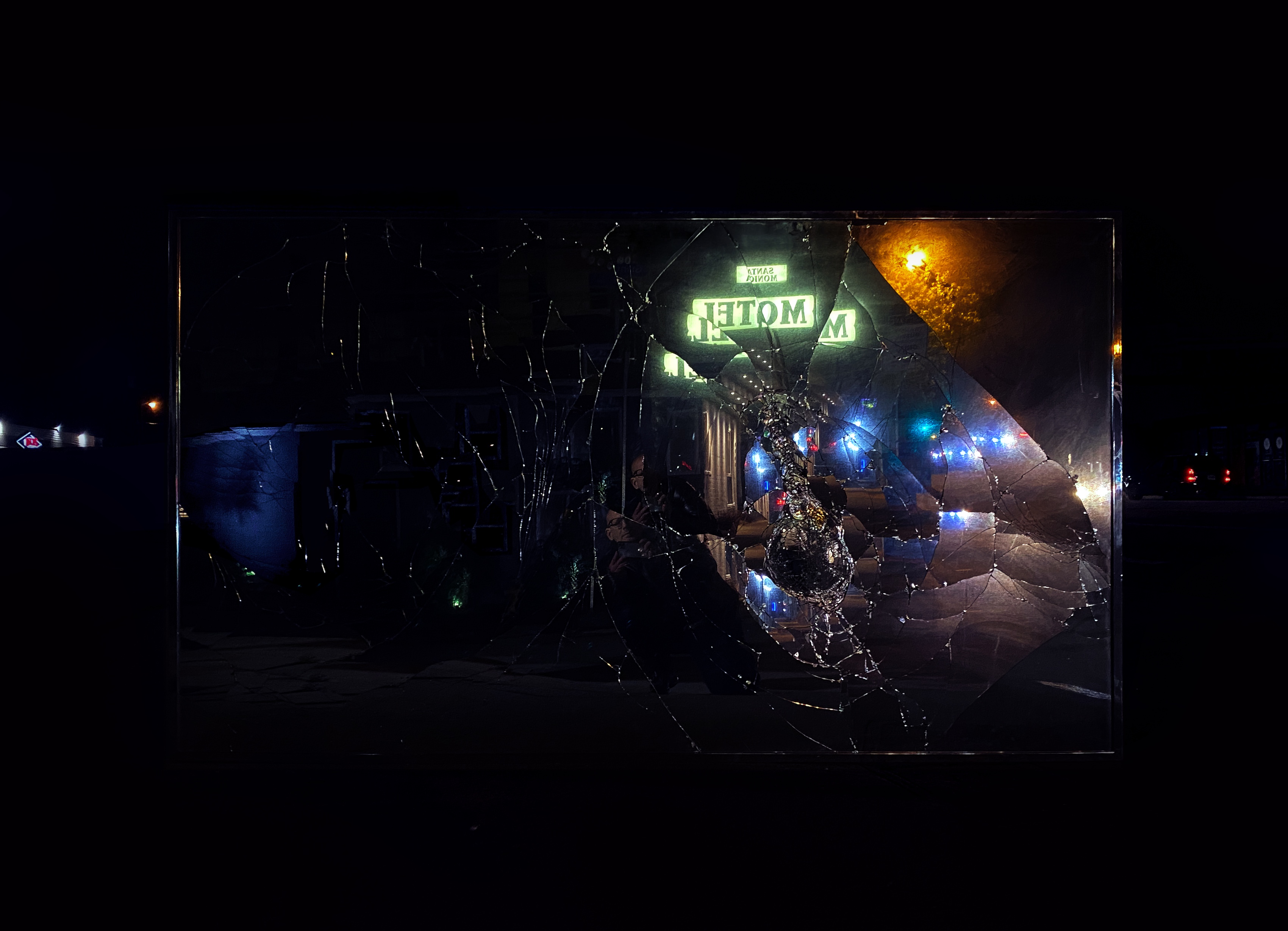 A night scene fractured and reversed in a broken mirror, a neon sign reflected back to front, from Van Eyssen's mirror works.